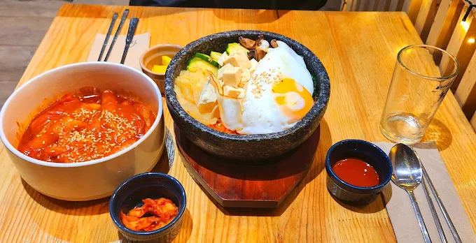 Dolsot bibimbap fumant avec œuf, légumes et kimchi, servi en bol de pierre